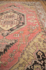 Vintage distressed Oushak carpet showing geometric vinery, serrated outlines, dusty pink, charcoal.