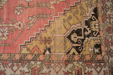 Distressed Oushak rug detail with geometric vinery, hook-and-latch, pink, saffron, charcoal.