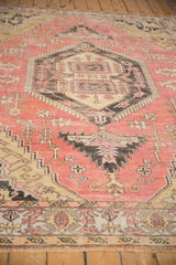 Distressed vintage Oushak with serrated geometric motifs, dusty pink, saffron, and charcoal tones.