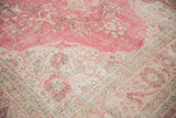 Distressed vintage Sparta carpet showing faded raspberry pink floral arabesques and ivory border.