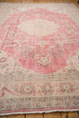 Textured distressed raspberry pink field, faded floral arabesques, and intricate beige borders.