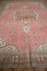 Distressed Sparta rug, abrashed pink field with vine floral pattern and visible foundation wear.