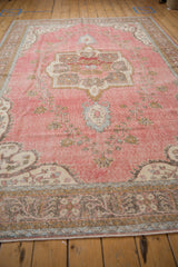 Distressed Sparta carpet corner: abrashed raspberry field, faded vine motif, and dusty blue border.