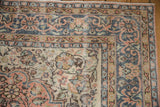 Distressed Sparta rug corner featuring denim blue borders, cantaloupe florals, and visible wear.
