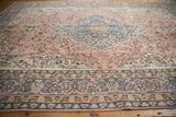Distressed Sparta rug detail: cantaloupe, ivory, denim blue vinery, florals, and worn texture.