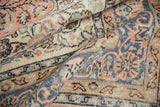 Distressed texture of a vintage Sparta rug with scrolling vinery, serrated leaves, cantaloupe, and denim blue.
