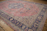 Distressed Sparta rug corner with dark cobalt blue floral vinery border, dusty pink field.