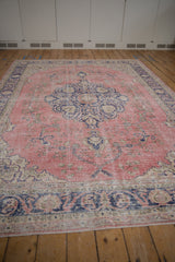 Textured dusty pink field with faded floral vinery and worn cobalt blue border.