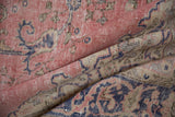 Decorative worn texture of distressed Sparta carpet, with dusty pink and cobalt blue motifs.