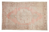 Vintage distressed Oushak carpet with a large medallion in dusty blush, ivory, and pale coffee brown tones.