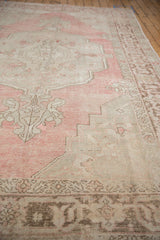A detailed Samovar border runs alongside the dusty blush field of a vintage Oushak carpet.