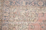Distressed vintage Sparta carpet showing faded pink floral arabesque border and worn blue motifs.