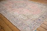 Distressed light pink field with visible wear alongside a dark blue floral arabesque border.