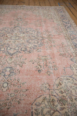 Distressed texture of a vintage Sparta carpet showing faded pink, slate blue floral motifs.