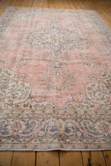 Distressed Turkish Sparta carpet, floral arabesque border, vinery in pink, ivory, blue hues.