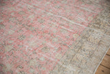 Blush pink field and beige border of the distressed Sparta carpet, showing faded patterns.