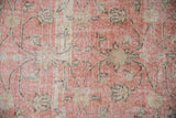 Blush pink and ivory Sparta rug, showing distressed scrolling vinery and foundation wear.