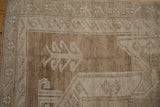 Distressed vintage Oushak carpet border, reciprocating wave motif with abrashes in beige and brown.