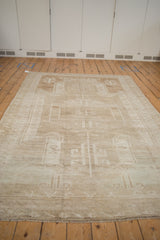 Distressed Oushak rug's secured end with worn fringe and pale beige tones.