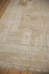 Distressed Oushak rug corner, revealing worn pile texture and intact side selvage.