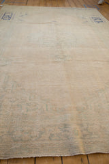 Low-angle view of the vintage Oushak carpet's soft, sandy pile and even wear.