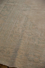 Detail of the distressed Oushak's low pile with even wear, showing sandy and pale sea foam tones.