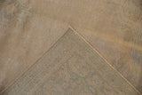The reverse of a distressed Oushak showing the hand-knotted foundation and worn, sandy pile.