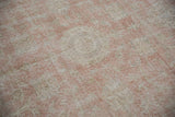 Worn knot heads and ivory foundation visible through the distressed dusty rose pile.