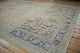 Vintage distressed Oushak carpet, featuring worn cobalt blue curvilinear pattern on cream field.