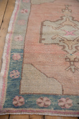 Vintage distressed Oushak rug: dusty rose pinwheel floral border on seafoam green, low pile.