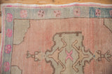 Distressed Oushak rug detail: abrashed pink ground, blossomed finial, pinwheel floral border.