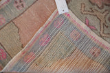 Distressed vintage Oushak rug's worn blush and green pile with striped hand-knotted reverse.