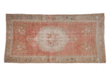 Distressed Oushak runner with pale red field, Rococo floral medallion, silver and beige borders.