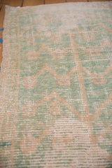 Worn low-pile texture of a vintage Tulu rug showing its mint green and ivory weave.