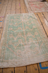 A vintage Tulu rug from a low angle, showing the distressed texture in mint green and ivory.