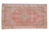 Distressed Oushak rug in faded blush, silver, ivory, and pale jade floral medallion.