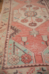 Distressed vintage Oushak runner with coral, mint, and ivory floral motifs, faint foundation.