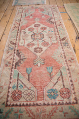 Distressed Oushak rug runner with coral, ivory, mint, and turquoise floral blossom medallion.