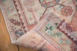 Folded vintage distressed Oushak rug shows intact side selvage and textural pile with faded colors.