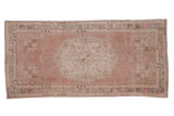 Distressed vintage Oushak runner with dusty rose, silver Rococo floral medallion. Measures 3'2