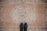 Vintage distressed Oushak runner's worn roundel medallion and Rococo floral motifs in dusty rose and ivory.