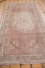 Distressed Oushak rug detail: dusty rose and ivory Rococo floral relief, low pile.
