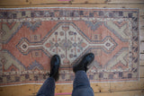Distressed Oushak runner's faded terracotta, beige, and aubergine patterns underfoot.