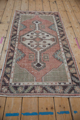 Geometric stepped medallion and distressed pile of vintage Oushak rug in rose, sage, ivory.