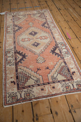 Distressed Oushak rug corner with faded terracotta, ivory, and geometric serrated patterns.