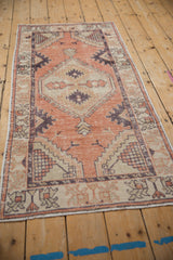 Distressed vintage Oushak runner showing pale terracotta field, dark aubergine serpent border, and even wear.