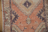 Distressed Oushak rug runner, showing terracotta field, serpent border, and intact side selvage.