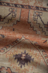 Distressed Oushak runner's texture and geometric patterns in pale terracotta, beige, and dark aubergine.