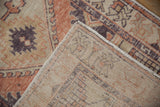 Distressed Oushak rug corner showing worn terracotta, aubergine pile, and hand-knotted foundation.