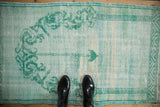 Distressed Oushak rug with mint and aqua scrolling vinery and time-softened texture.